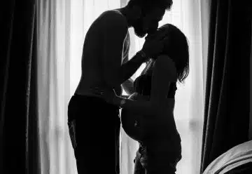 man standing near window kissing woman