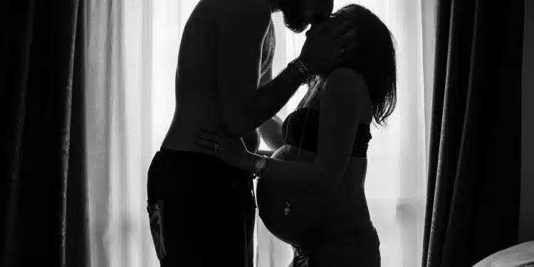 man standing near window kissing woman